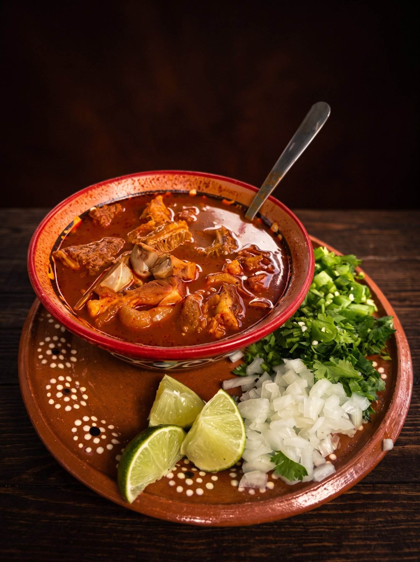 Caldo de camarón in a clay bowl with green peppers and a spoon