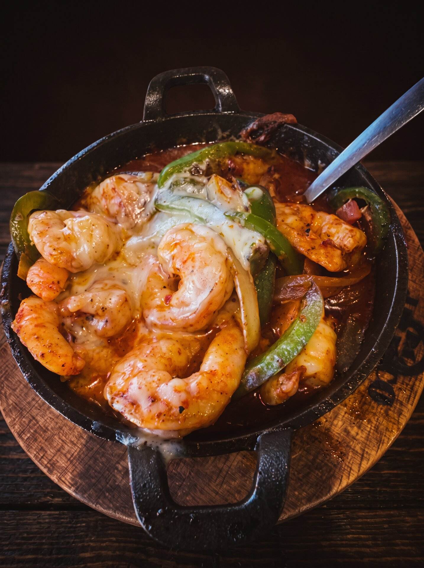 Shrimp grilled with onions and bell peppers in a cast-iron skillet