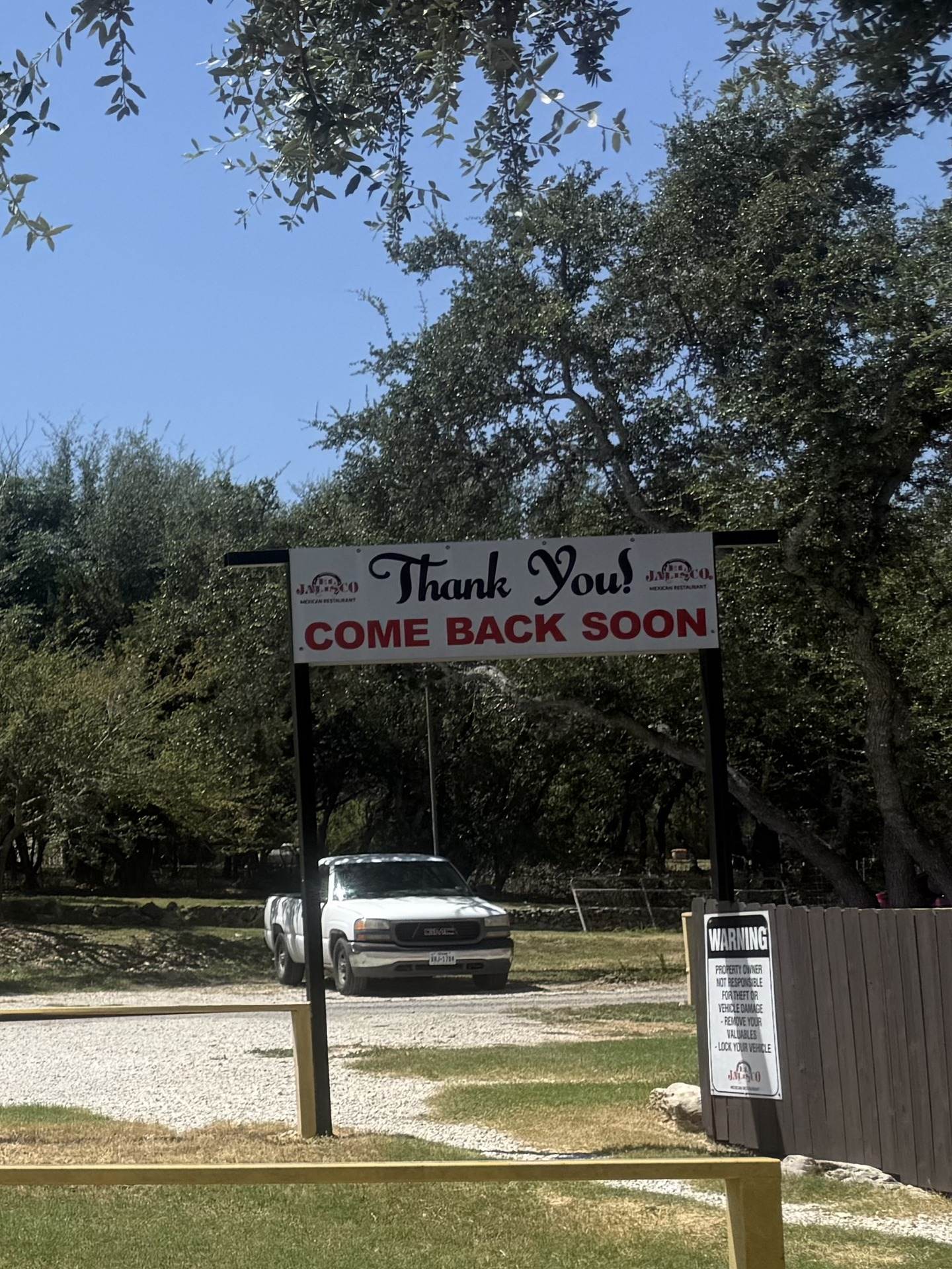 The Thank You, Come Back Soon banner at the exit of the lot, under the live oaks