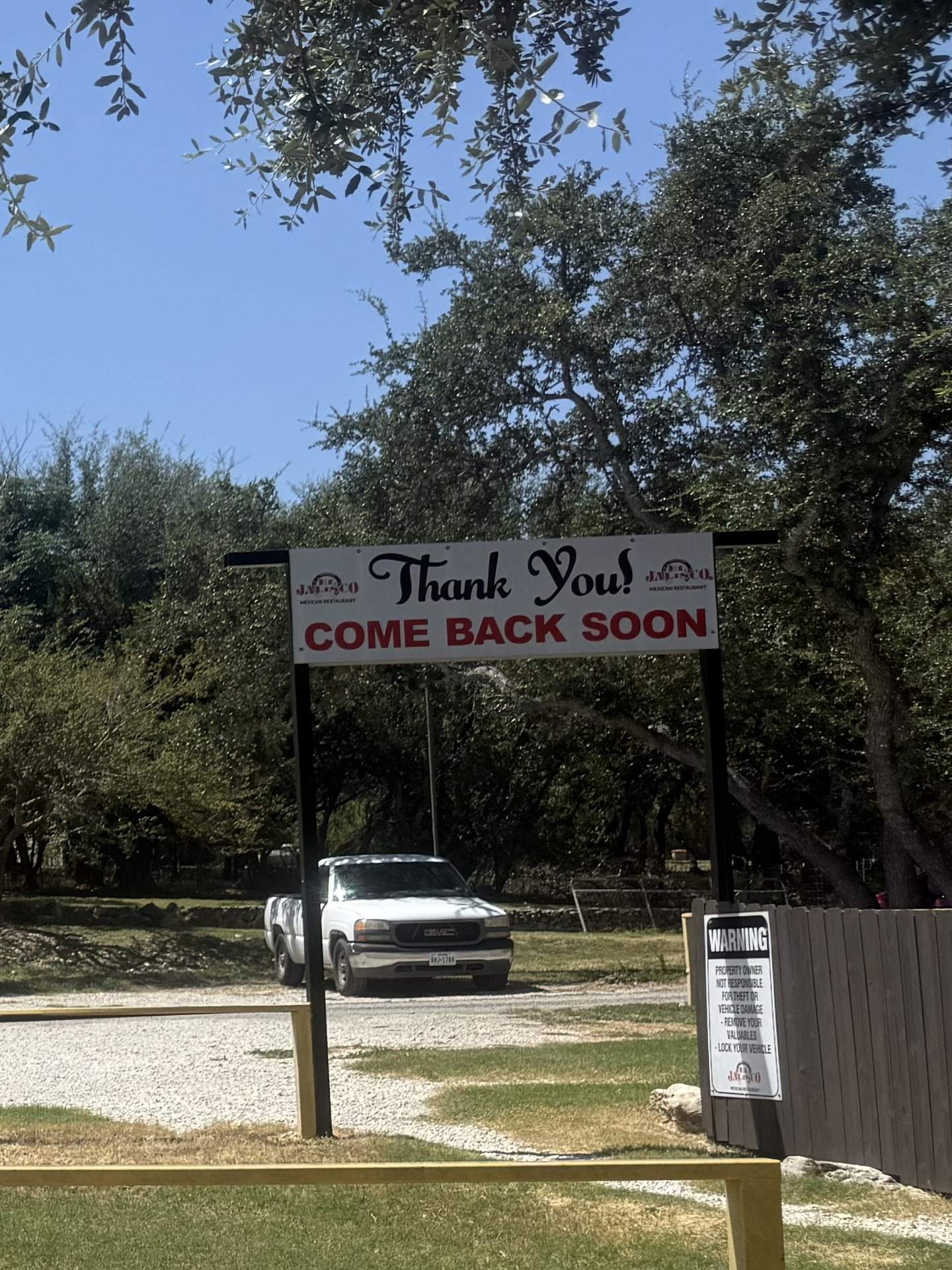 The Thank You, Come Back Soon banner at the exit of the lot, under the live oaks