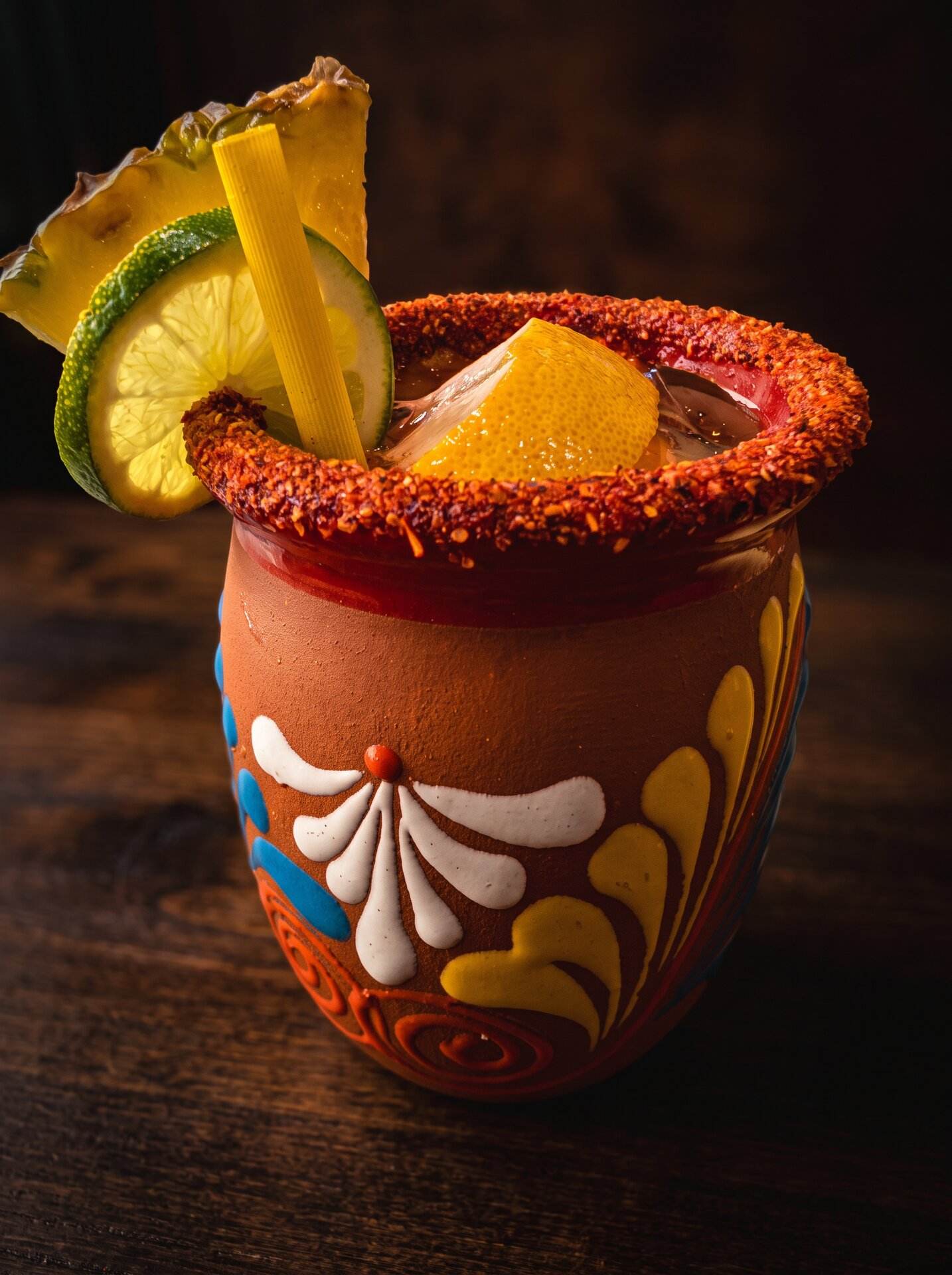A michelada in a hand-painted Talavera mug with pineapple, lime and a chile rim