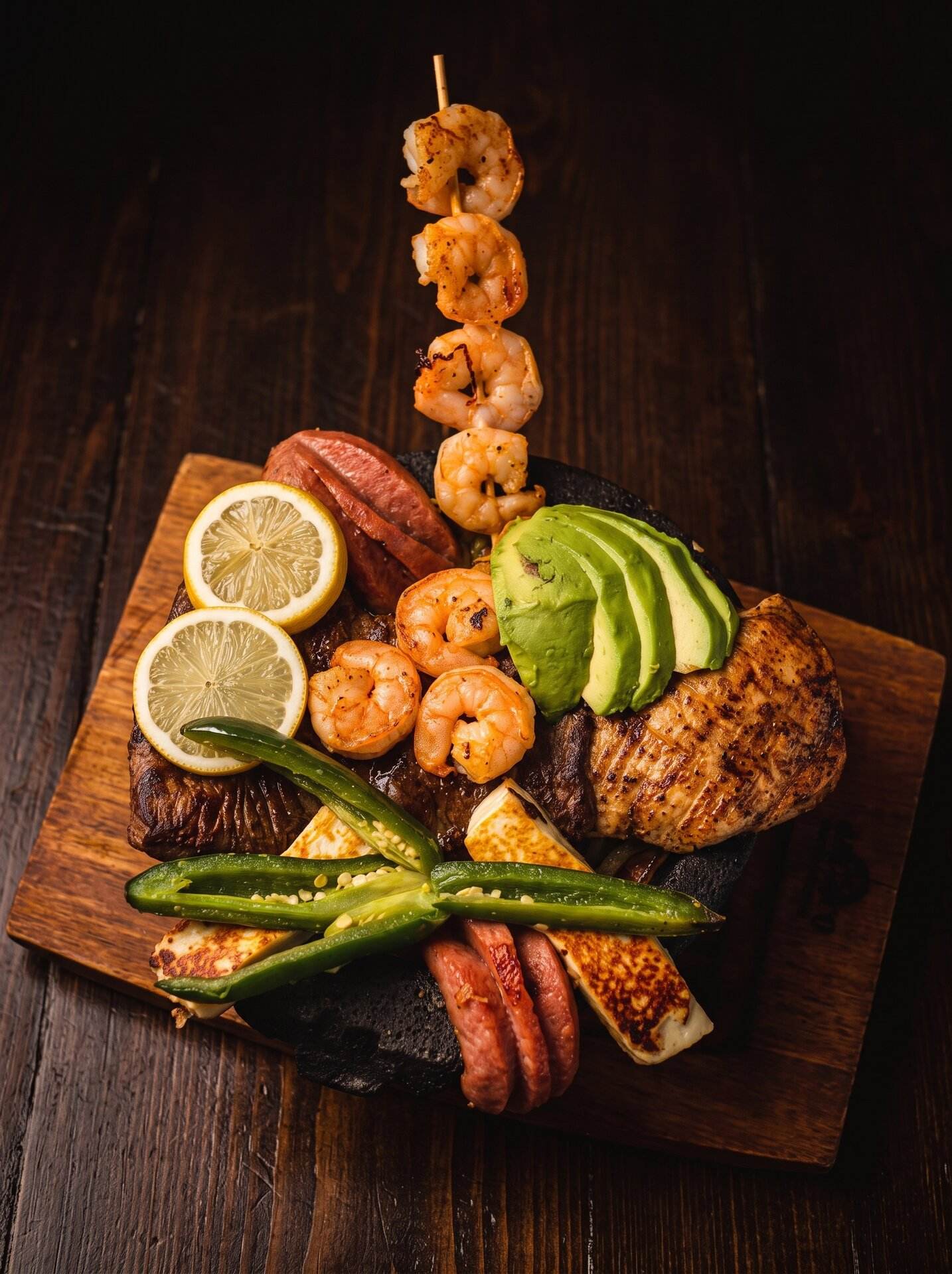 Parrillada served on a wooden board with a shrimp skewer, sausage, avocado and lemon