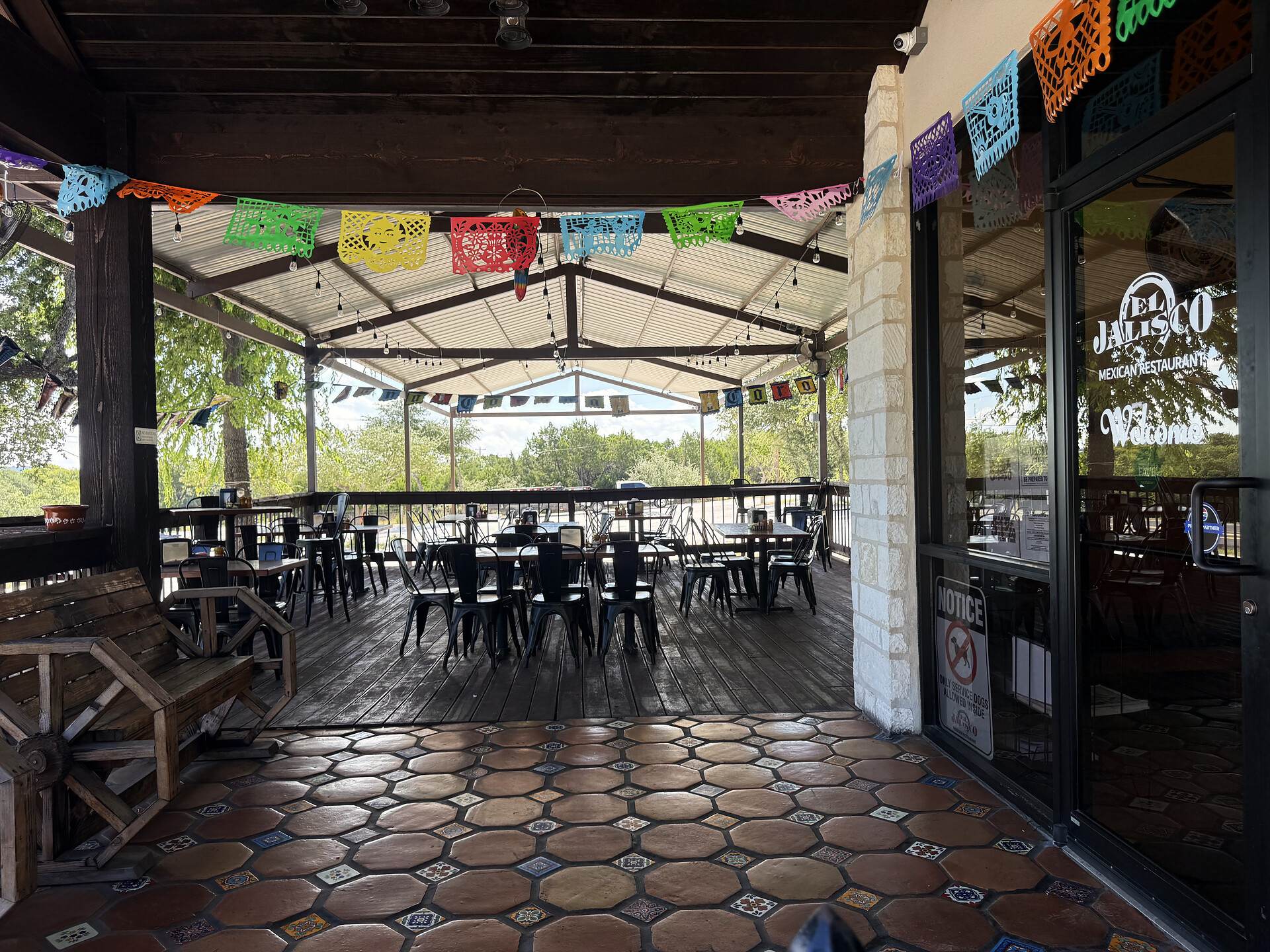 The covered patio under its white gabled roof, papel picado strung between the beams